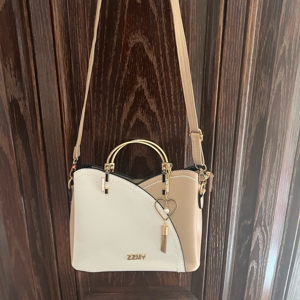 Small crossbody purse with gold hardware. Gold carry straps and longer tan strap